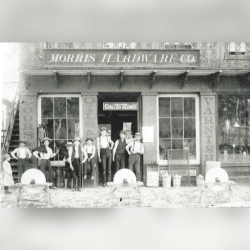 Black-and-white photo of seven men in work clothes standing in front of 